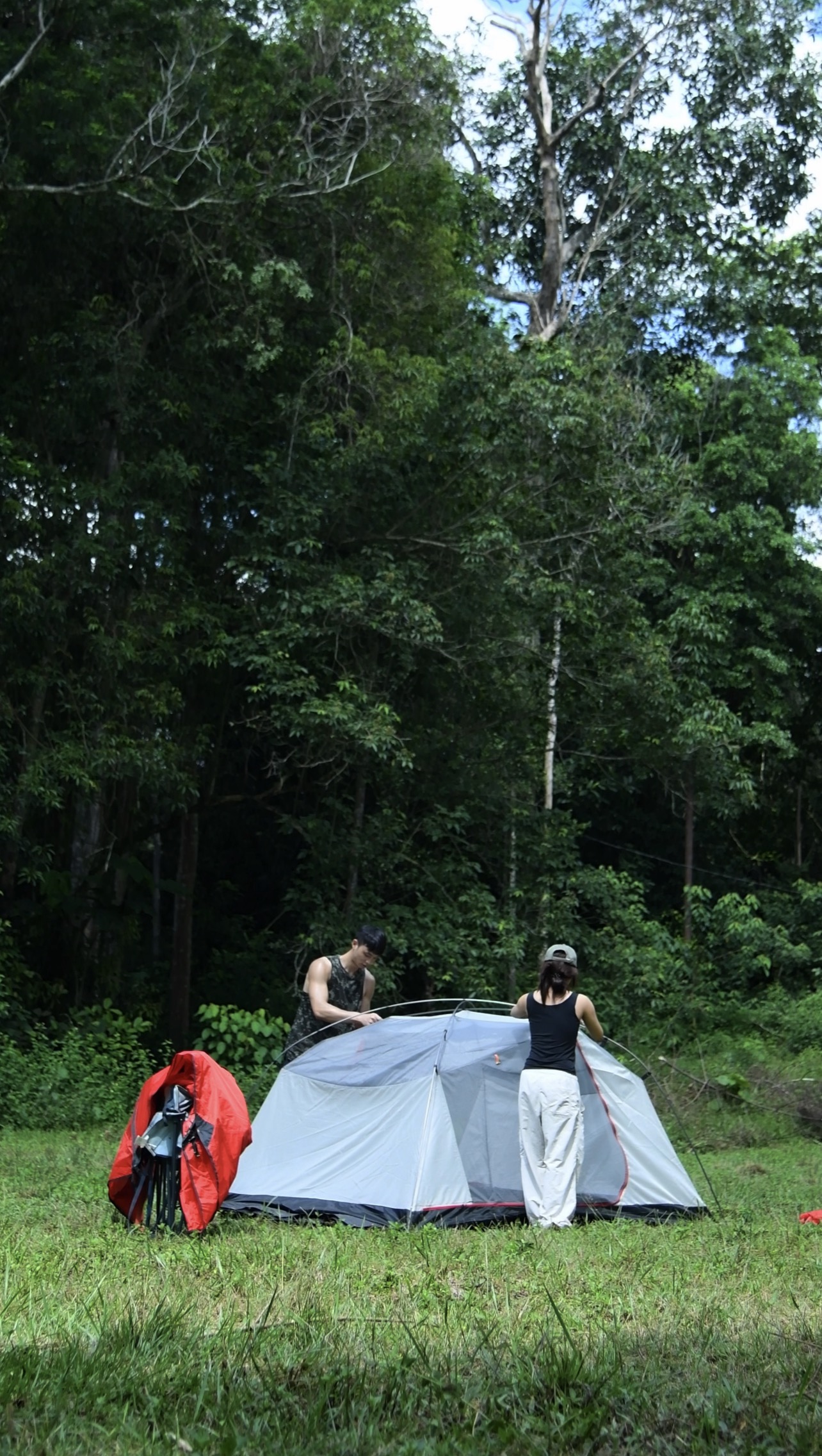 Two campers pitching a tent in the forest